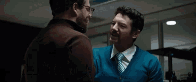 two men are standing next to each other in an office and one of them is screaming at the other .