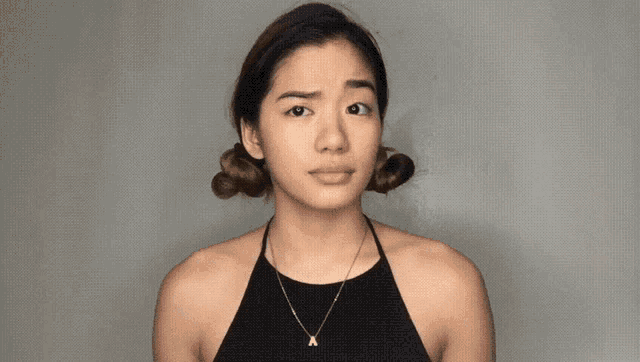 a woman wearing a black top and a gold necklace with a letter a on it