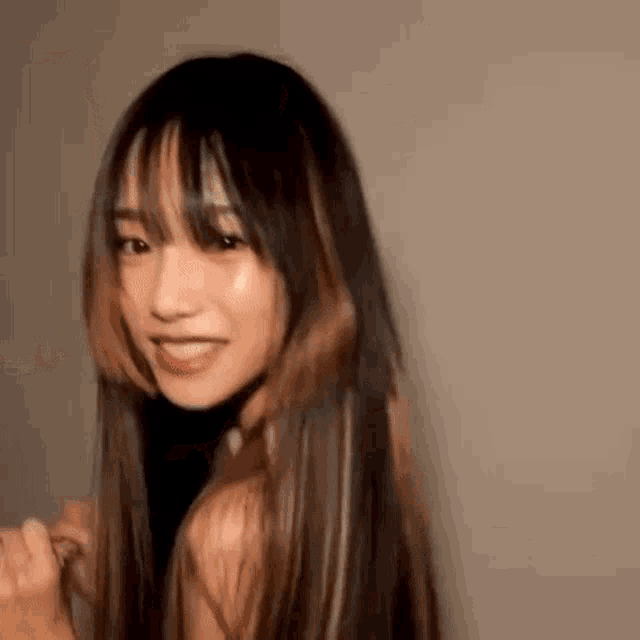 a close up of a woman with long hair and bangs smiling .