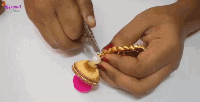 a person is holding a piece of jewelry in their hands and cutting it with a knife .