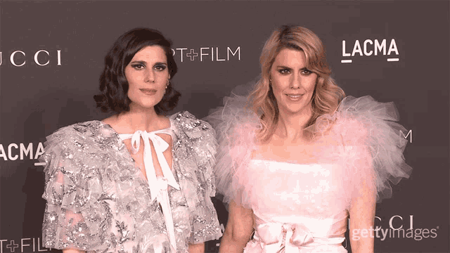 two women standing next to each other in front of a sign that says lacma