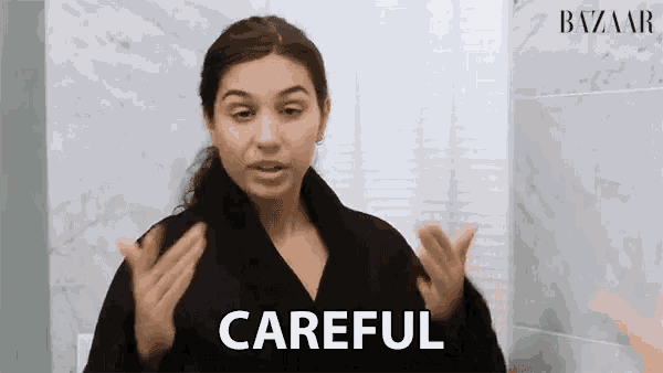 a woman in a black robe is making a gesture with her hands and says careful .