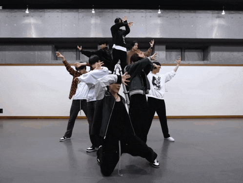 a group of people are dancing in a room with a white wall