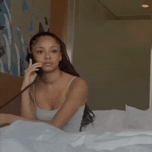 a woman sitting on a bed talking on a telephone