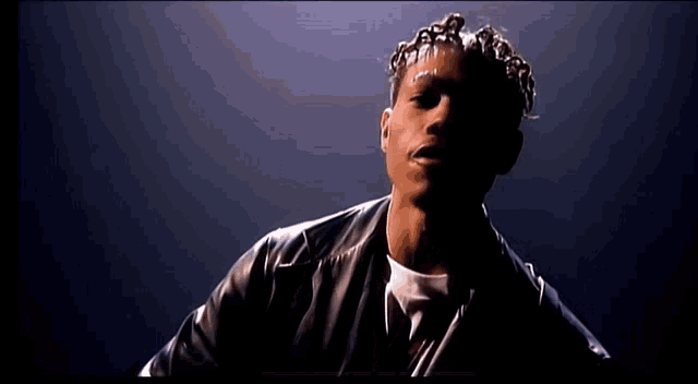 a man with dreadlocks and a black leather jacket looks at the camera