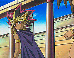 a cartoon character with a purple cape standing next to a pillar