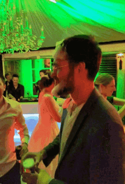 a group of people are dancing in a room with green lighting