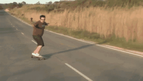 a man is riding a skateboard down a road with a car behind him