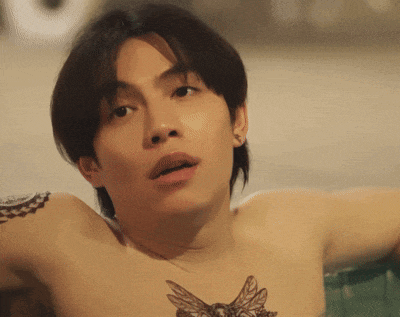 a shirtless man with a tattoo on his chest is looking at the camera