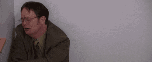 a man in a suit and tie is sitting in a corner with his arm outstretched