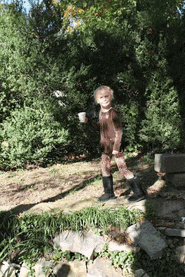 a little girl standing on a rock holding a cup in her hand