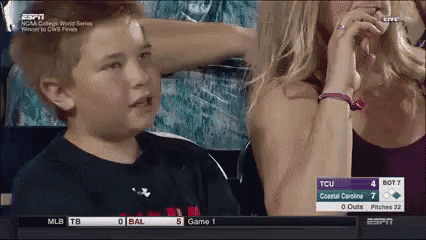 a boy is sitting in a stadium watching a baseball game between tcu and bal