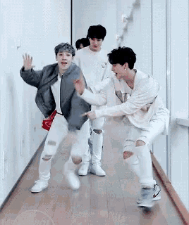 a group of young men are dancing in a hallway and one of them is wearing a shirt that says supreme
