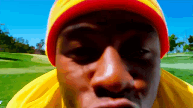 a man wearing a yellow shirt and a red hat is looking at the camera