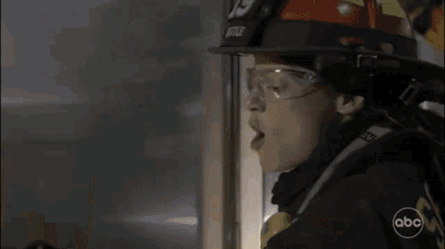 a fireman is cutting a hole in a wall with a saw .