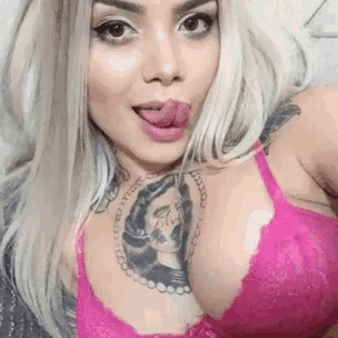 a woman with a tattoo on her chest is wearing a pink bra .