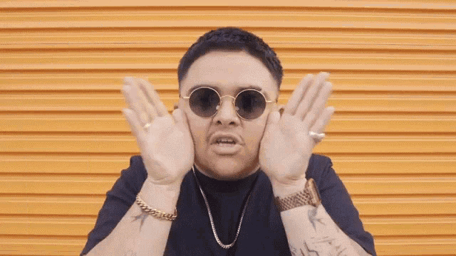 a man wearing sunglasses is making a funny face and the words shut yo up are behind him