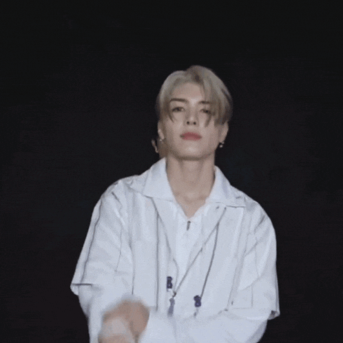 a young man in a white shirt is dancing in a dark room