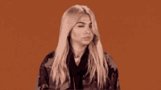 a woman with blonde hair is wearing a black jacket and a scarf .