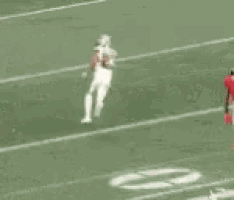 a group of football players are running on a field with one wearing the number 15