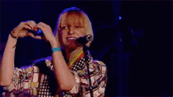 a woman singing into a microphone while wearing a colorful shirt