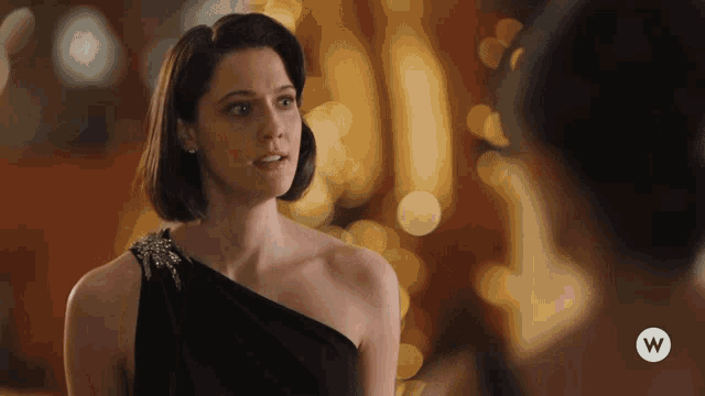 a woman in a black dress with a w logo on the bottom right