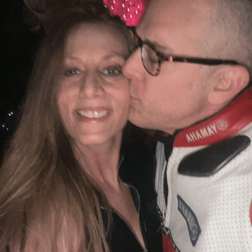 a man kissing a woman on the cheek wearing a jacket that says ahamay