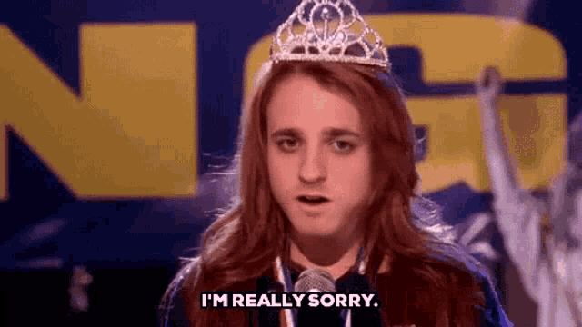 a woman with long red hair wearing a tiara and a medal says i 'm really sorry