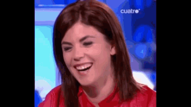 a woman in a red shirt is laughing while sitting on a stage .