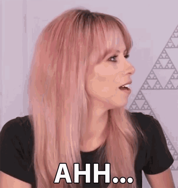 a woman with pink hair is making a surprised face and saying ahh .