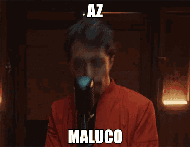 a man in a red jacket is singing into a microphone with the name maluco written on the bottom