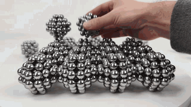 a person is playing with a bunch of metal balls on a table