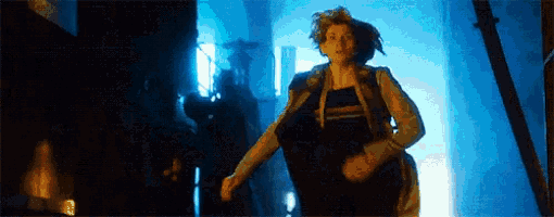 a woman is running in a dark room with a blue light .