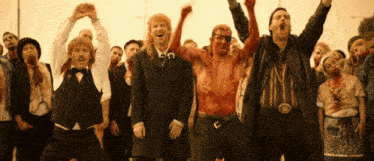 a group of men with blood on their bodies are standing in a crowd with their hands in the air