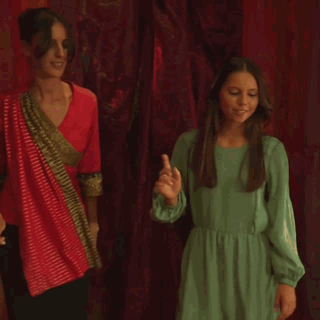 a woman in a red top is dancing with another woman