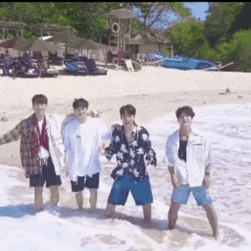 a group of young men are standing on the beach .