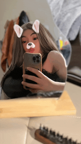 a woman is taking a picture of herself in a mirror with a dog filter on her face