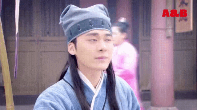 a man wearing a blue hat and a blue robe is sitting in front of a building .