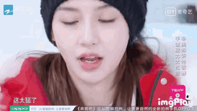 a woman wearing a black hat and a red jacket is on a screen that says oppo r15