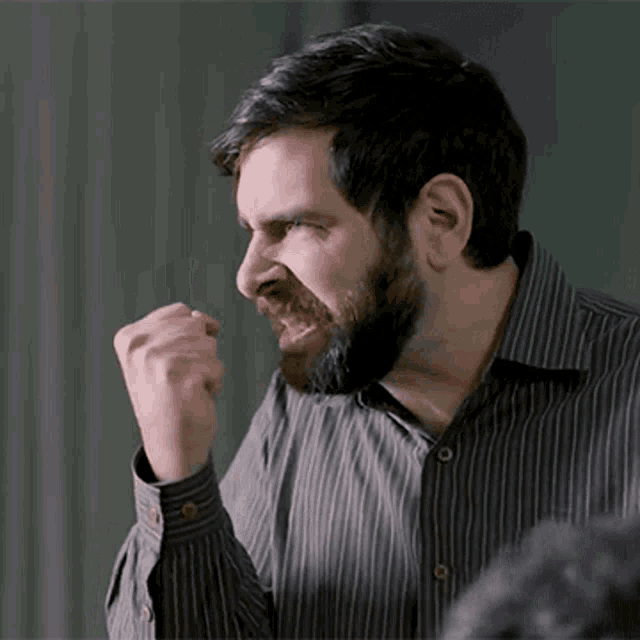 a man with a beard wearing a striped shirt is making a fist