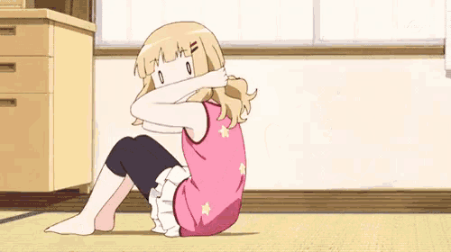 a girl is sitting on the floor with her legs crossed and her face covering her eyes .