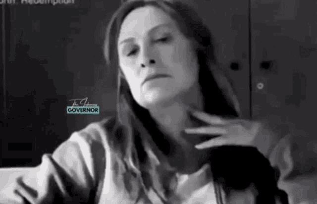 a woman is sitting on a couch with her hand on her neck and looking at the camera .