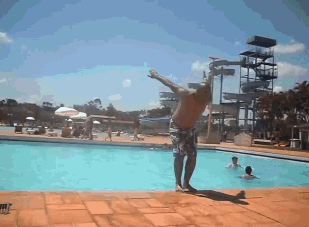 a man is doing a handstand in a pool with a water slide in the background