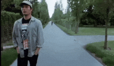 a man wearing a hat is walking down a road .