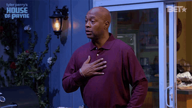 a man stands in front of a sign that says tyler perry 's house of payne on it
