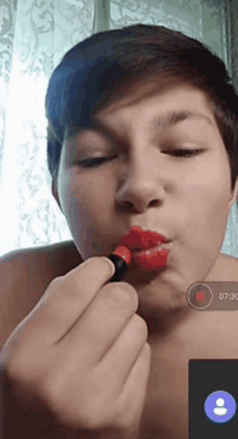 a man is applying red lipstick to his lips