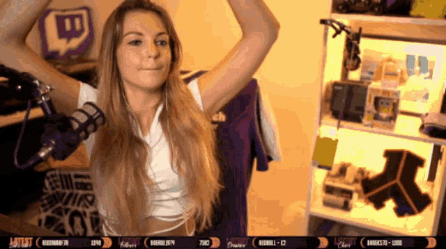 a woman stands in front of a microphone in front of a twitch logo
