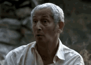 a man with gray hair and a white shirt is making a funny face