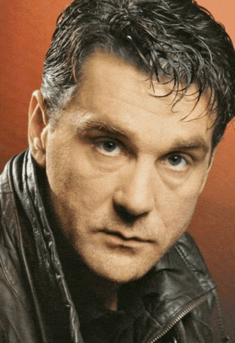 a man in a leather jacket looks at the camera
