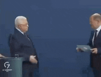two men in suits and ties are shaking hands while standing next to each other .